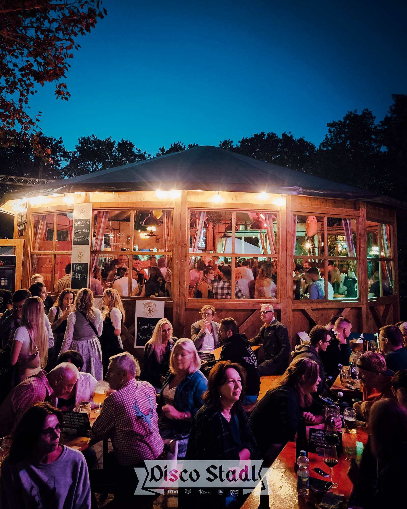 Disco Stadl bei Nacht mit Gästen im Außenbereich